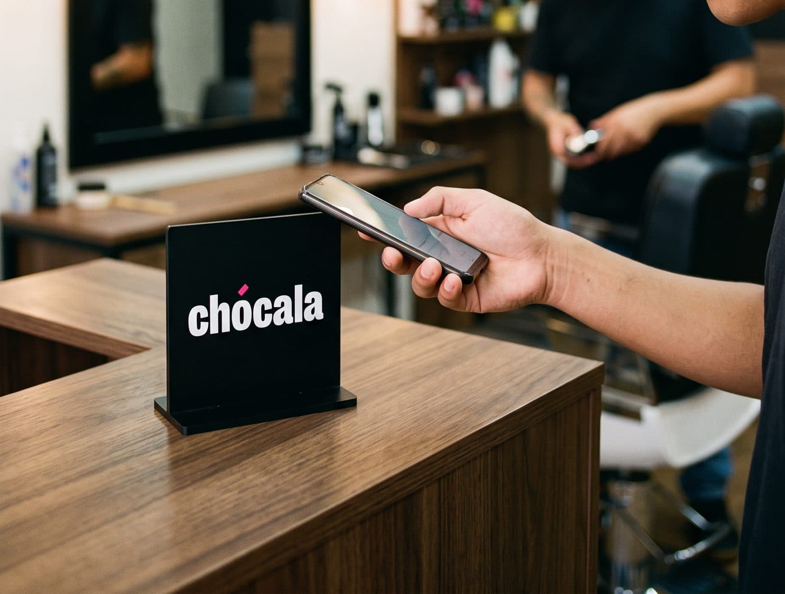 Cliente en una barbería acercando su celular al soporte de Chócala