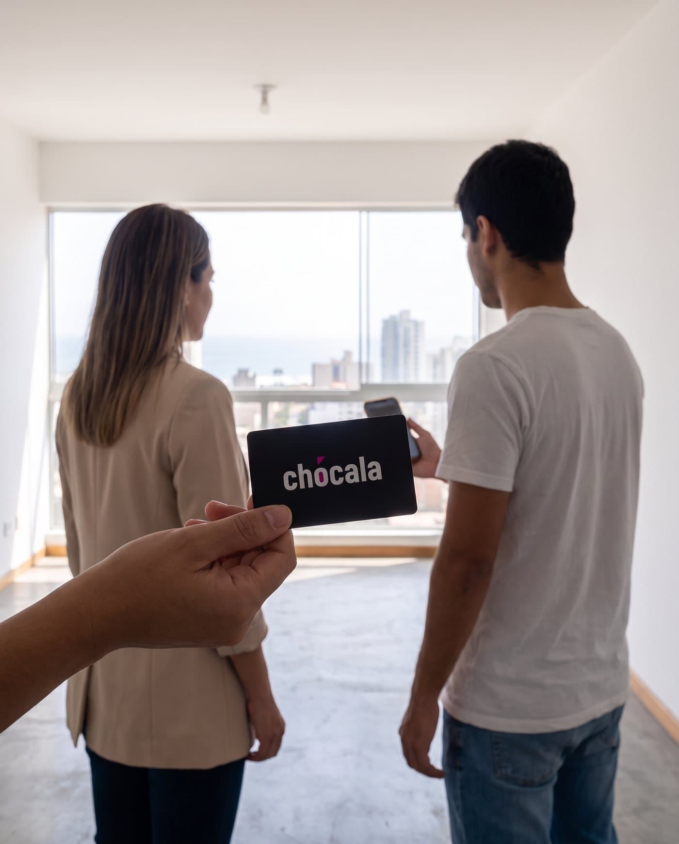 Asesora y cliente de espaldas en un departamento vacío; una mano sostiene la tarjeta negra de Chócala